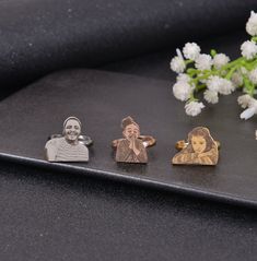 three different types of cufflinks on a table with flowers in front of them