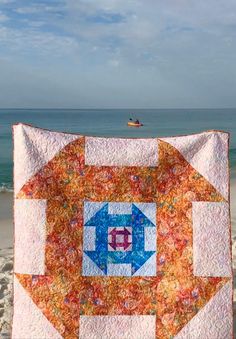 an orange and blue quilt on the beach