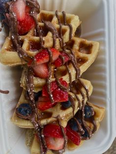 waffles topped with strawberries and chocolate drizzled on the top