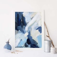 an abstract painting is displayed on a shelf next to a blue vase and other items