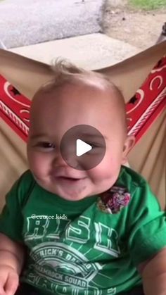 a baby sitting in a hammock smiling at the camera with his mouth open