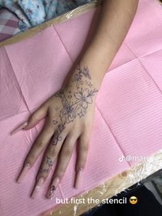 a person's hand with tattoos on it sitting on top of a pink mat