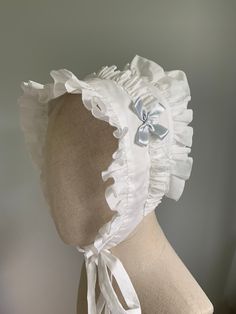 "This listing is for a made-to-order frilled cotton bonnet cap, suitable for periods c1820 to 1840. The cap is sized to fit adult heads from 21\" to 23\" - larger or smaller sizes available upon request. Inside the back of the cap is a drawstring and bow, to allow for adjustment on the head, and also to facilitate easier pressing after laundering. The cap is made from a light cotton lawn, and can be starched if you need to (I don't starch the caps myself). It features cotton bonnet strings (ties) to fasten to the head, and an optional satin bow detail, on either one side or both. The bow in the sample is blue, but other colours are available. There are two versions of the bonnet cap -machine sewn and hand sewn. The bonnet in the sample photos is machine sewn, but put together in a way that Adjustable Cotton Vintage Bonnet, Fitted Cotton Bonnet With Lace Trim, White Cotton Bonnet, One Size Fits Most, White Cotton Bonnet For Baptism, Adjustable Cotton Bonnet With Lace Trim, Adjustable Costume Bonnet, Adjustable Ruffled Bonnet, Adjustable White Hat With Ruffles, Adjustable White Ruffled Hat