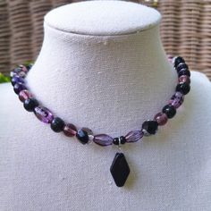 A Witchy And Whimsical Bohemian Glass Choker Necklace. Crafted With Various Shades Of Purple Czech Glass Beading, Faceted Black Czech Glass Beading, Painted Black Wood Beading, And A Striking Diamond-Shaped Black Ceramic Pendant At The Center. Handmade By Me, One Of A Kind. Hypoallergenic Stainless Steel Chain And Clasp. Nickel Free. Total Length: 14.5 Inches Length Of Chain: 13 Inches Extender Length: 1 Inch. If You Require A Longer Extension Chain To Ensure A Proper Fit, Please Let Me Know! Ju Black And Purple Necklace, Purple Festival Jewelry With Black Beads, Purple Jewelry With Black Beads For Festival, Purple Necklace With Black Beads, Adjustable Purple Necklace With Black Beads, Purple Necklace With Black Beads For Gift, Handmade Purple Beaded Choker Necklace, Handmade Purple Choker Necklace, Purple Bohemian Jewelry With Black Beads