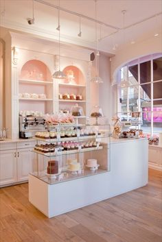 a bakery filled with lots of cakes and cupcakes on top of glass shelves