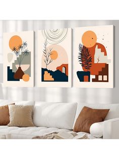 three abstract paintings hang on the wall above a white couch in front of a window