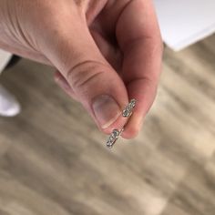 a person is holding their finger up to show the diamond ring on her left hand