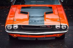 an orange and black muscle car parked on the street