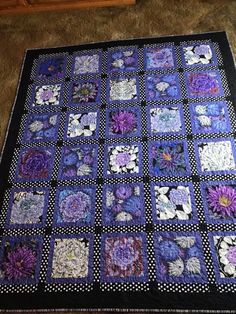 a purple and black quilt with flowers on it