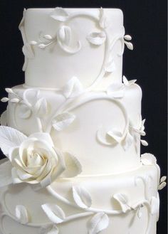 a white wedding cake sitting on top of a table next to a cell phone screen