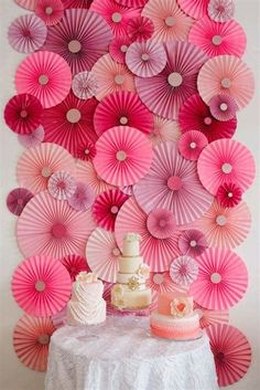 a table topped with cake and pink paper fans