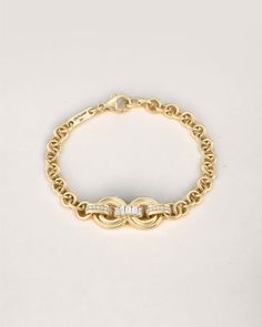 a yellow gold chain bracelet with an oval clasp and diamond accent, on a white background