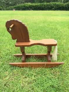 a wooden rocking horse sitting on top of a lush green field