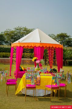 a table set up for a party with pink and yellow decorations