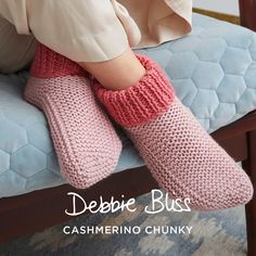 a woman sitting on top of a blue couch wearing pink knitted slippers and socks