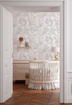 a baby's room with a white crib and wallpaper in the background