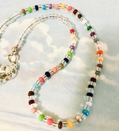 a multicolored beaded necklace with a heart charm hanging from it's end