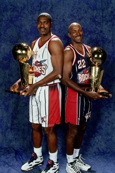 two basketball players holding trophies in their hands