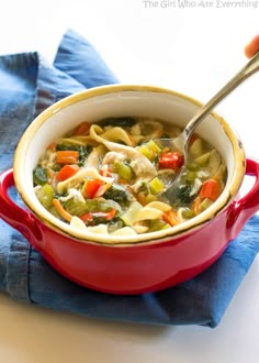 a red pot filled with pasta and veggies on top of a blue napkin