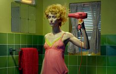 a woman in a pink dress blow drying her hair with a red blow dryer