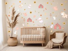 a baby's room with a crib, chair and wall decals