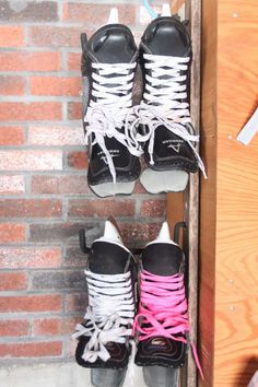 two pairs of ice skates sitting on top of each other in front of a brick wall