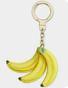 a banana keychain is hanging from a metal hook on a white background,