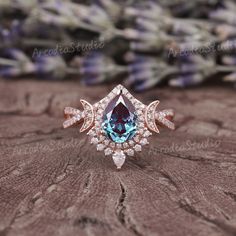 a blue and white diamond ring sitting on top of a piece of wood with lavender flowers in the background