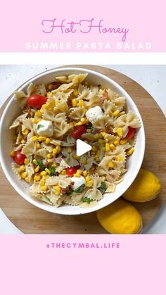 a white bowl filled with pasta and vegetables on top of a wooden cutting board next to lemons