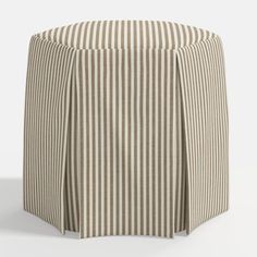 a round ottoman cover with stripes on it's sides and an open pleated skirt