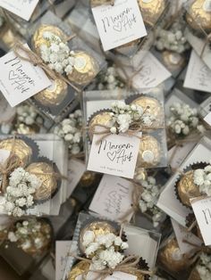 many small boxes filled with white flowers and gold foil wrapped in twine ribbons, tied together