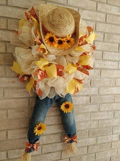 a scarecrow with sunflowers on it's back hanging against a brick wall