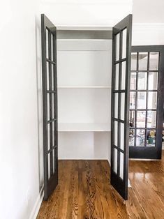 an empty room with open doors leading to another room that has wood floors and white walls