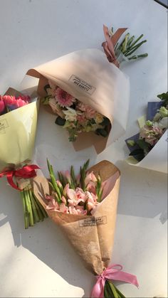 three bouquets of flowers are wrapped in brown paper