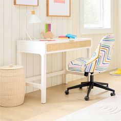 a white desk with a colorful chair next to it and a basket on the floor