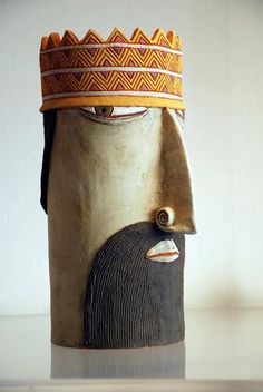 a ceramic head with a yellow crown on it's head and an orange band around its neck