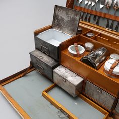 an open wooden box with silverware and other items in it on a table next to utensils