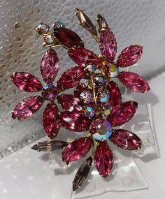 "Collectible jewelry. Check out the store's reduced prices.  Ask for a discount if you love the item. Ask for fast shipping if the item is a gift. Now listed is a vintage  Judy Lee Sparkling Pink Fuchsia Colors Prong Set AURORA BOREALIS Huge Rare Navette & Round Stones Brooch 1950s Era. This stunning piece comes from a long line of HIGH END Judy Lee JEWELRY. This piece is designed with an array of beautiful Aurora Borealis glass stones in gorgeous colors.   The brooch is a must have for Judy Lee Retro Pink Jewelry For Formal Occasions, Pink Retro Style Jewelry For Formal Occasions, Red Retro Brooch Jewelry, Retro Red Brooch Jewelry, Vintage Pink Jewelry For Anniversary, Pink Vintage Jewelry For Anniversary, Elegant Pink Brooches For Collectors, Mid-century Flower Jewelry Gift, Vintage Flower Shaped Jewelry For Party