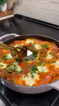 a skillet filled with cheese and sauce on top of a stove next to a spatula