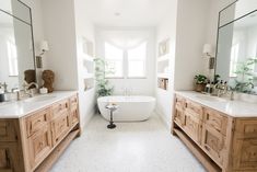 a bathroom with two sinks and a bathtub in the middle, along with mirrors on both sides