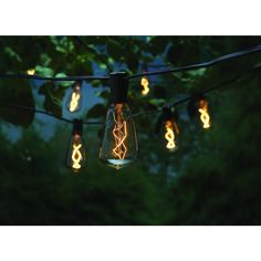 some light bulbs are hanging from a wire in the dark, with trees behind them