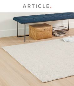 a white rug on the floor next to a blue bench with a basket under it