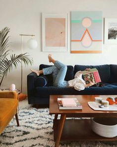 a woman laying on top of a blue couch in a living room