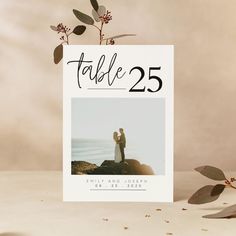 a table number card with a couple holding each other's hands on top of a rock