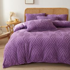 a bed with purple comforters and pillows in a room