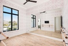 an empty living room with wood floors and large mirrors on the wall, along with a ceiling fan