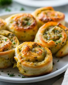 several small rolls on a white plate with parsley sprinkled around the edges