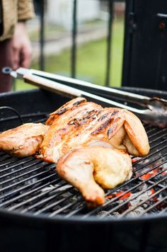 some chicken is cooking on a grill with tongs