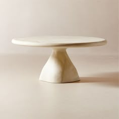 a white cake plate sitting on top of a beige tableclothed flooring area