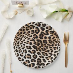 an animal print plate next to goldware and flowers